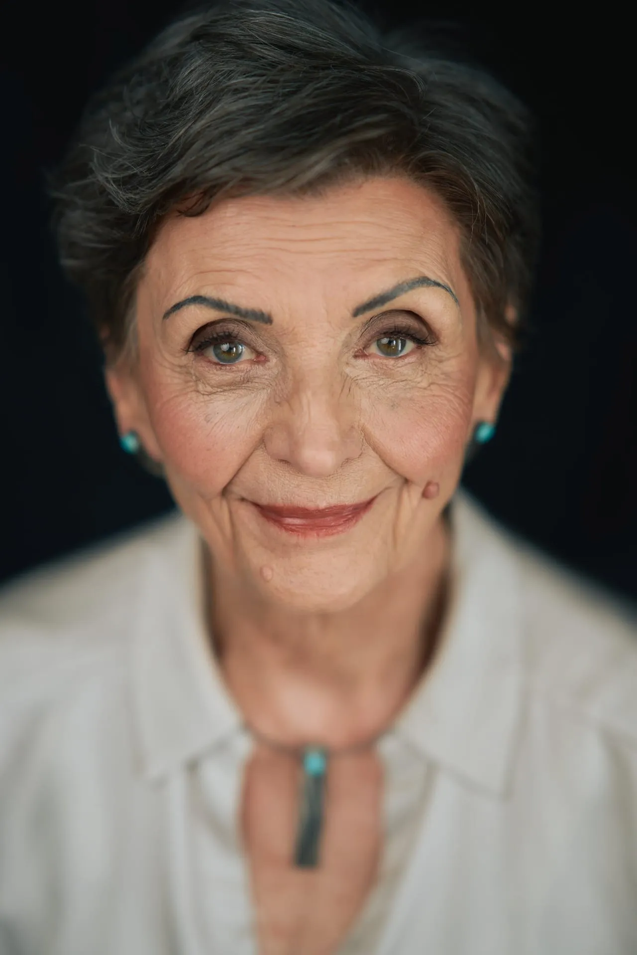 Portret uśmiechniętej kobiety z krótkimi włosami na czarnym tle