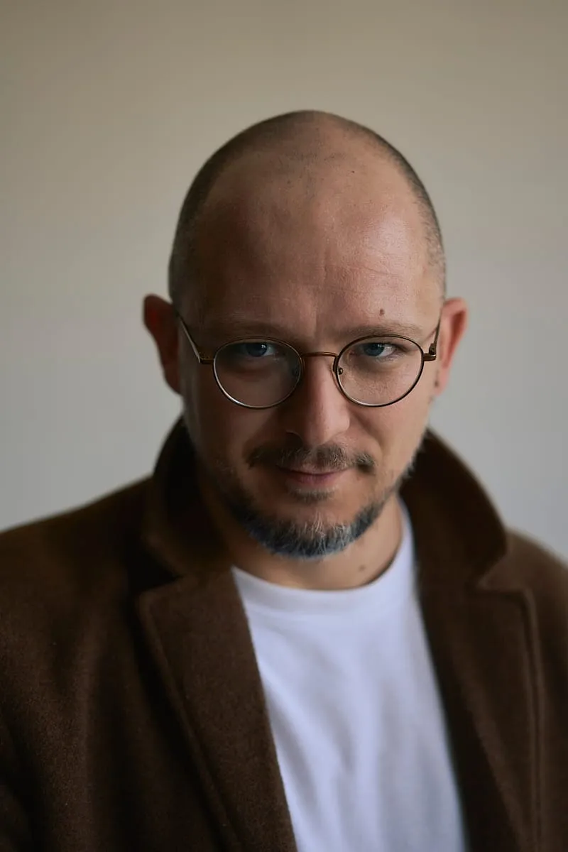 Portret mężczyzny w okularach i brązowym płaszczu