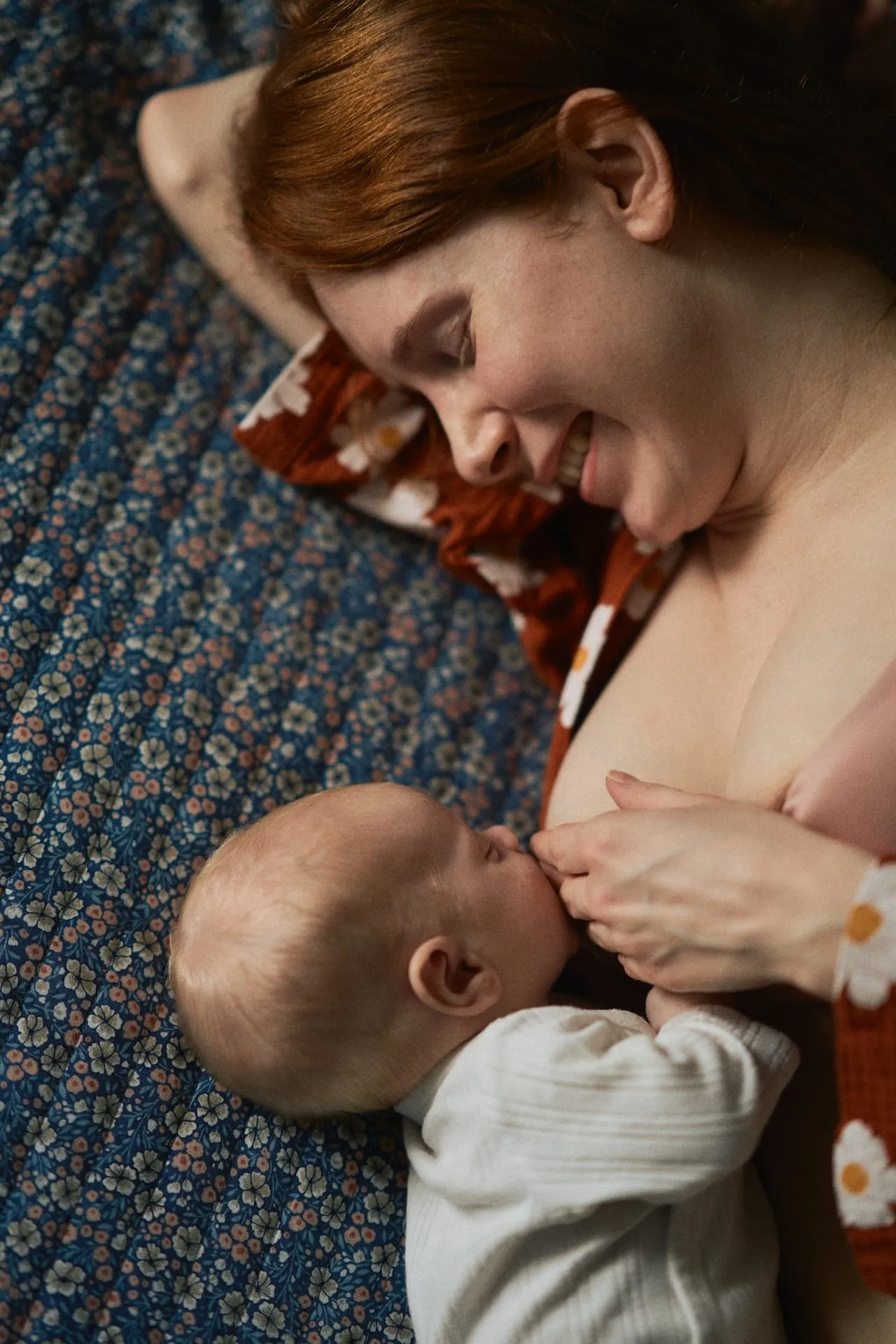 Roześmiana mama karmiąca niemowlę na łóżku