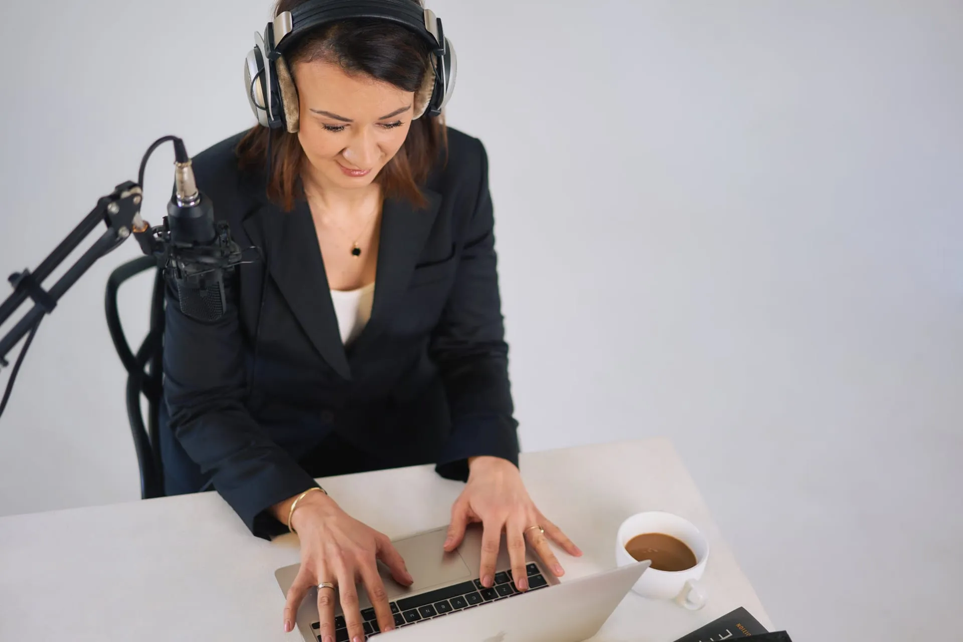 Kobieta w słuchawkach przy mikrofonie podcastowym i laptopie