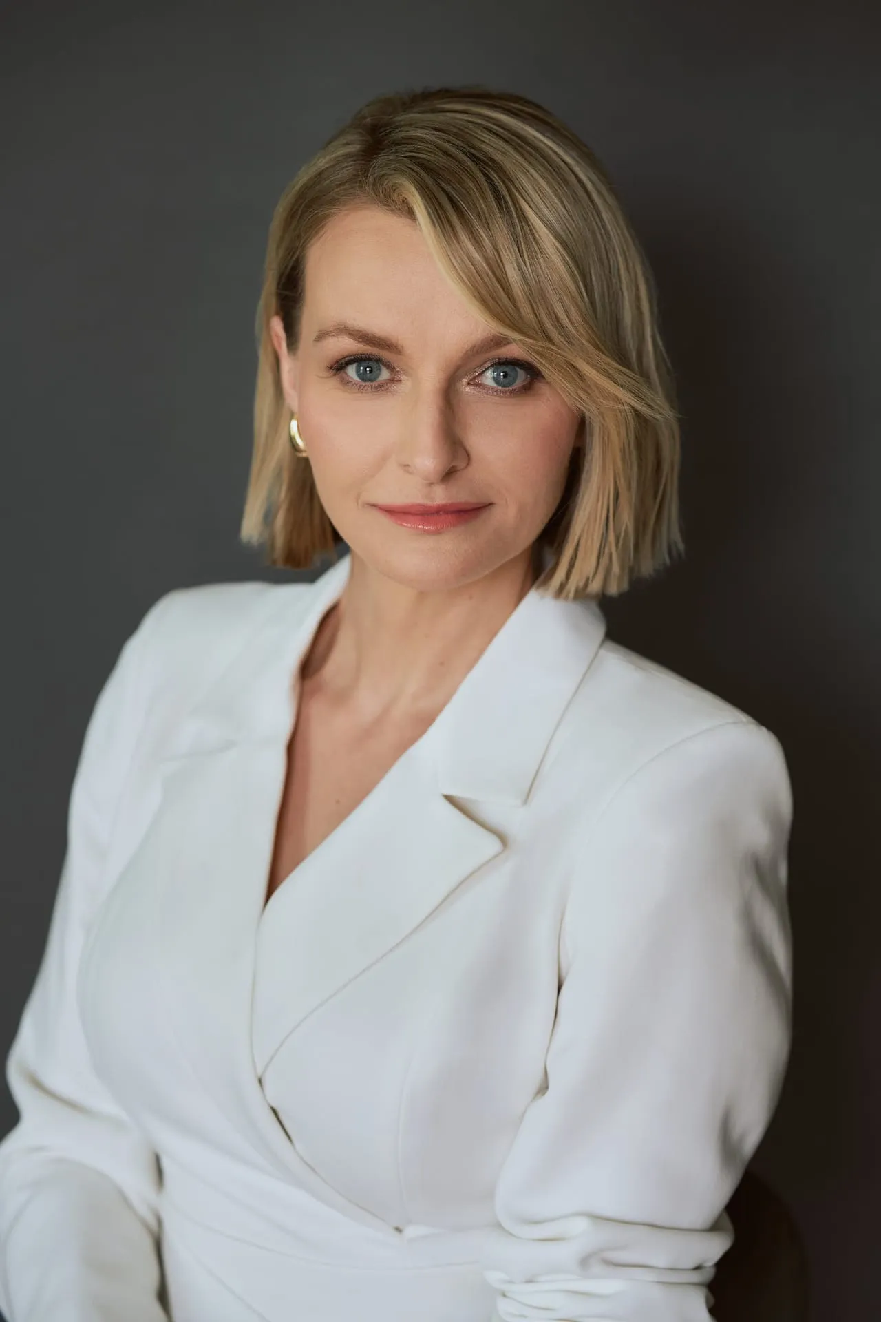 Portret kobiety w białej marynarce na ciemnym tle