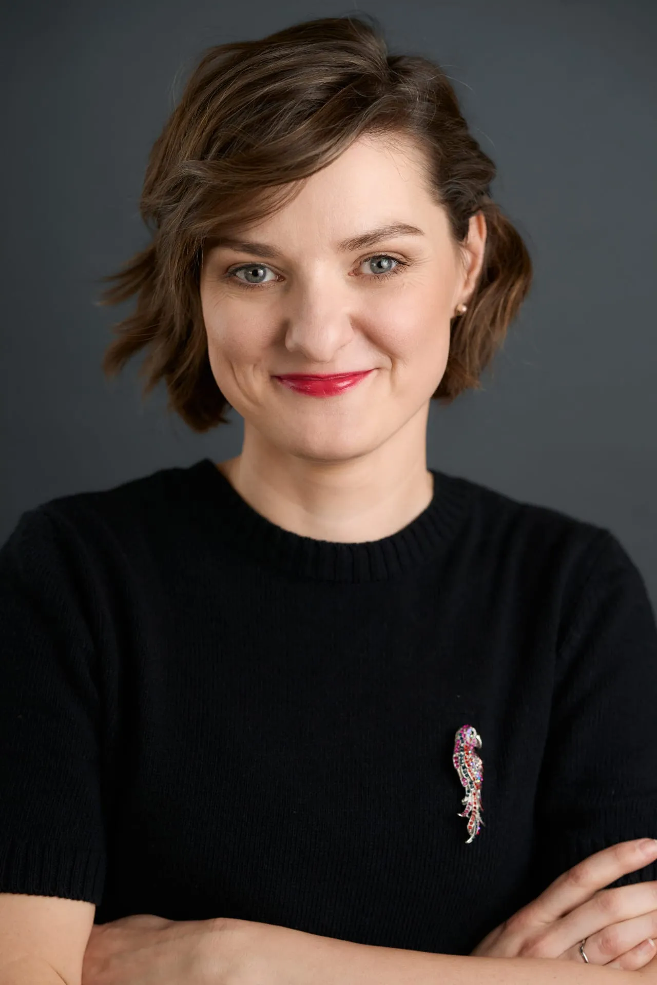 Portret kobiety w czarnym swetrze z ozdobną broszką